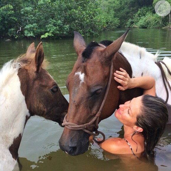 Gisele Bündchen postou uma foto tomando banho com dois cavalos em um rio