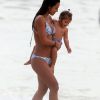 Yanna Lavigne carrega a filha no colo e brinca com a menina na praia