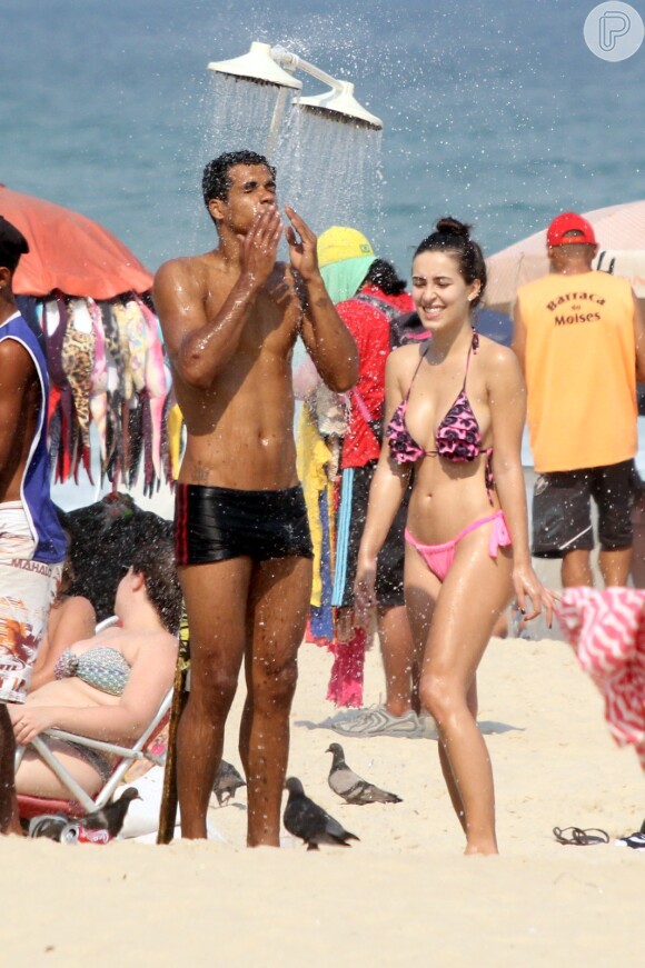 Entre um beijo e outro, Marcello Melo Jr. a namorada, Caroline Alves, se refrescaram no chuveirão da praia