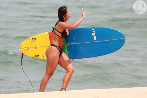 Carol Nakamura foi clicada segurando prancha em praia do Rio