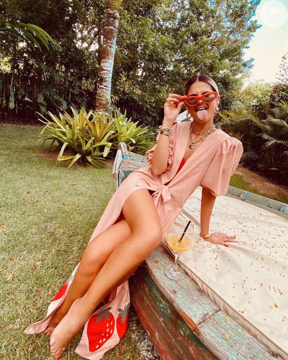 Moda praia das famosas: a influencer Thássia Naves apostou em óculos retrô com armação vermelha, mix de colares e saída de praia fashionita, com manga bufante e estampa de morangos