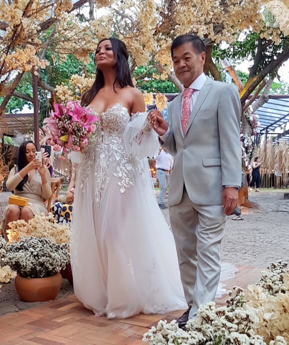 Carol Nakamura foi levada ao altar pelo pai, San Nakamura, e usou um vestido tomara que caia com transparência nas mangas