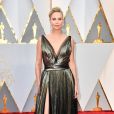 A elegância de Charlize Theron no Oscar 2017 com vestido ouro sob camadas de tule preto e decote profundo com fenda na saia