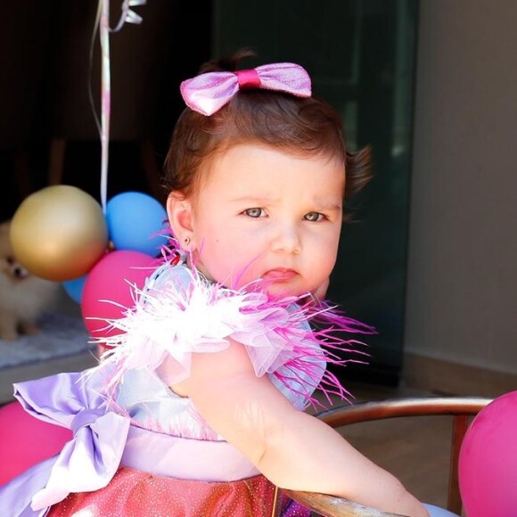 Filha de Zé Neto usa vestido rosa com plumas, laços e estrelas