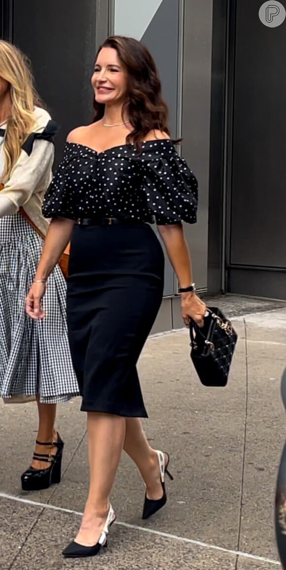 A personagem Charlotte usa blusa ombro a ombra de poás Carolina Herrera, minibag Lady Dior e scarpins J'Adior com alças de cetim