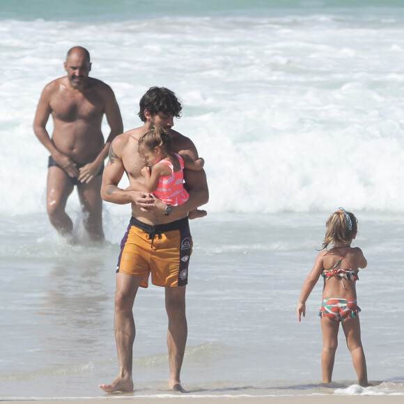 Chay Suede, sem Laura Neiva, carregou a filha de dois anos no colo enquanto ele e o amigo se refrescavam no mar