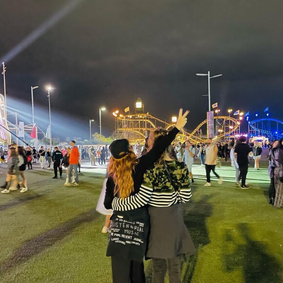 Fernanda Souza e Eduarda Porto aparecem abraçadas diante da montanha russa do Rock In Rio