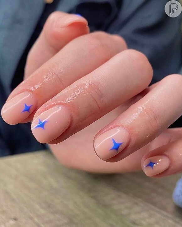 Unhas decorada com esmalte clarinho e detalhes azuis: essa nail art é fácil de fazer para Copa do Mundo
