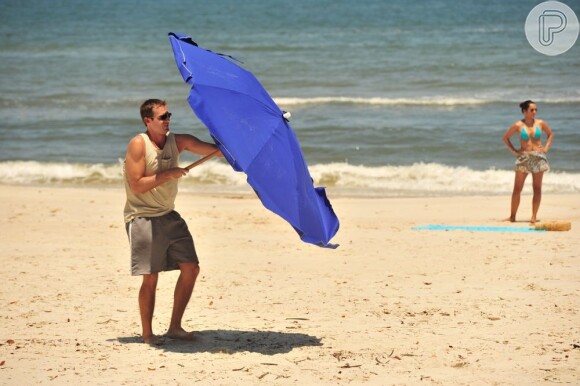 Ciro (Max Fercondini) se atrapalha com o guarda-sol na praia, em 'Flor do Caribe'