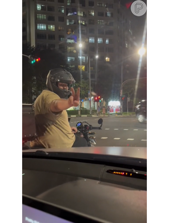 Motociclista faz sinal de paz ao ser filmado fazendo carinho no carro ao lado