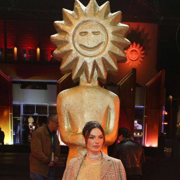 Isis Valverde usa sobretudo xadrez por cima de vestido dourado brilhante que deixa seus seios à mostra no Festival de Cinema de Gramado