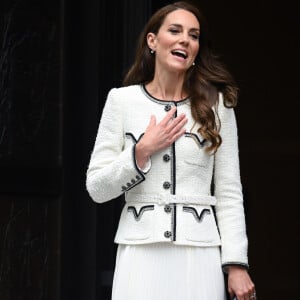 Kate Middleton combinou agasalho de frio e saia midi plissada nesse look branco com detalhes pretos