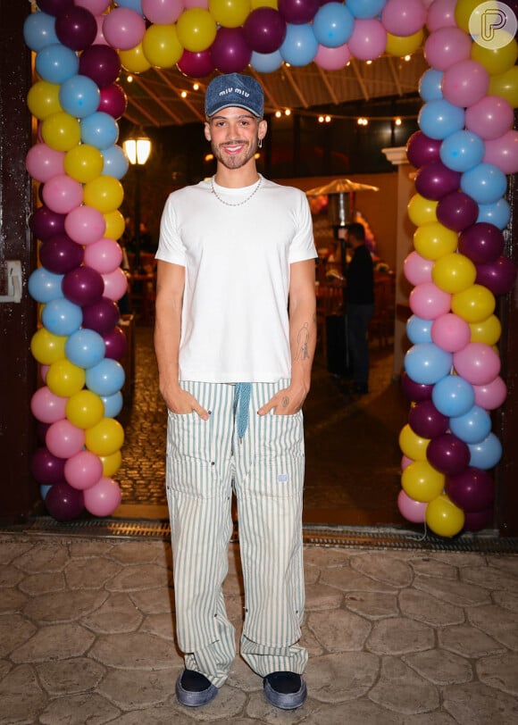 Já João Guilherme escolheu uma combinação de calça oversized listrada e camiseta branca, com boné jeans