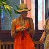 Débora Nascimento exibiu as pernas em um look estiloso, composto por short, blusa laranja, sandálias rasteiras, chapéu, bolsa de franjas e muitos acessórios, como colares e pulseiras