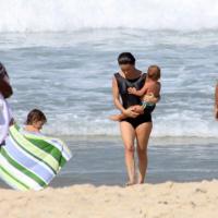 Cláudia Abreu curte domingo de sol na praia com a família exibindo maiô discreto