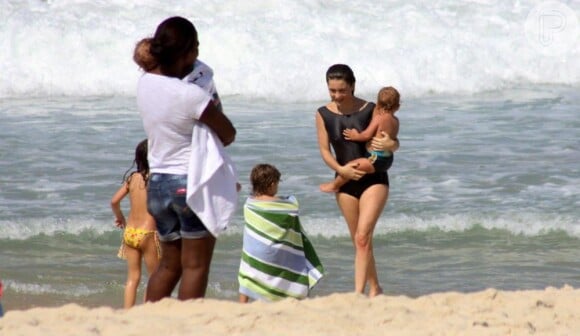 Cláudia Abreu usou um maiô retrô para curtir a manhã na praia ao lado da família