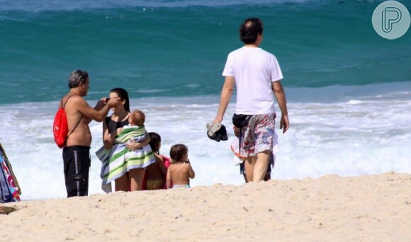 Cláudia Abreu não descuida das crianças e enrola na toalha para proteger do frio ao deixar o mar