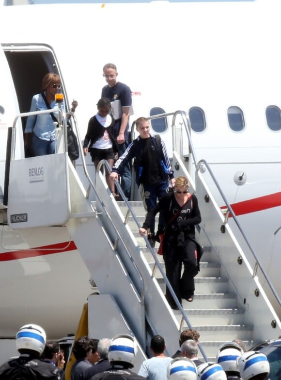Madonna desce as escadas do avião acompanhada por seus filhos