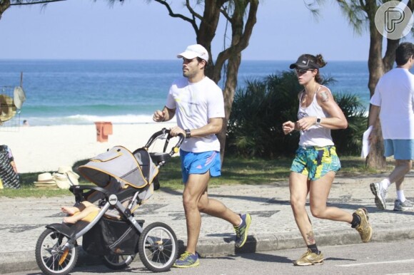 Juliano Cazarré corre empurrando um carrinho com o seu filho Inácio, de quase 10 meses, acompanhado pela mulher, Letícia Bastos, em 7 de junho de 2013