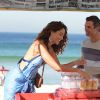 Carlos Alberto (Marcos Pasquim) ajuda Regina (Camila Pitanga) em sua barraca de praia, em cena da novela 'Babilônia'