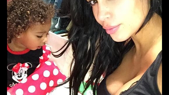 Kim Kardashian exibe seu decote e cachinhos da filha, North, com cara de sono