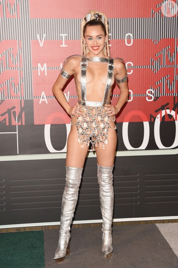 Miley Cyrus é mais uma famosa que adora ousar em seus looks. A popstar usou diversos figurinos para apresentar o Video Music Awards (VMA) 2015, como este da foto, composto por um suspensório prata, que tampava apenas seus mamilos, e uma tanga de material transparente