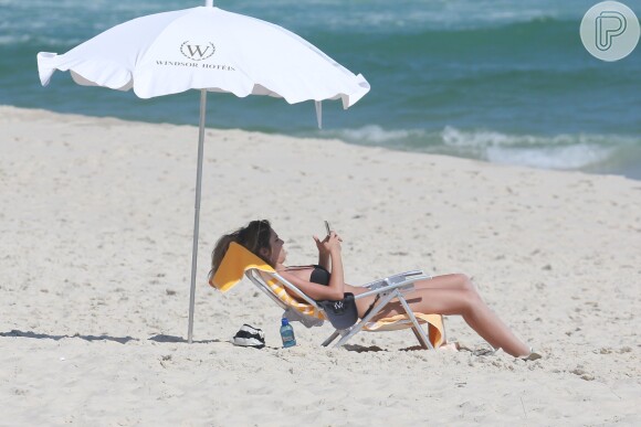 Rafa Brites mexe no celular durante passeio na praia