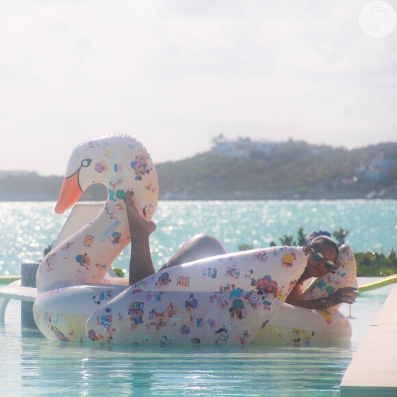 Em uma boia de cisne, Rihanna se bronzeou enquanto tomava drinks na piscina