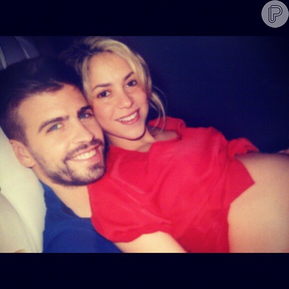 Shakira no colo do marido, Gerard Piqué, mostrando a barriga de sete meses de gravidez em novembro de 2012