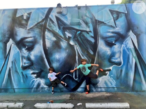 Filhos de Claudia Leitte, Davi e Rafael, posam em frente a uma das pinturas com o rosto da mãe nos Estados Unidos