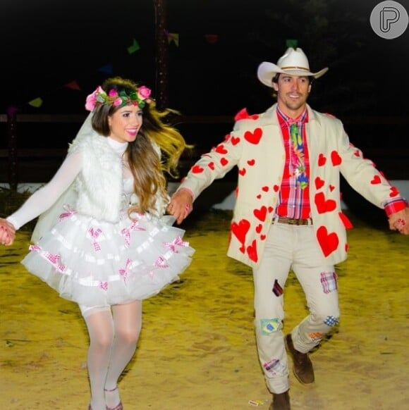 A cantora Paula Fernandes usou vestido branco com lacinhos rosa para ser noiva em uma festa de São João ao lado do noivo, Henrique do Valle