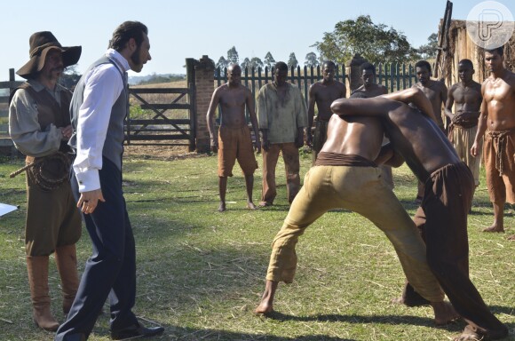 Zé Leão (Marcelo Escorrel) e Almeida (Fernando Pavão) observam uma luta entre escravos, na novela 'Escrava Mãe', em 27 de junho de 2016