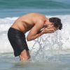 Cauã Reymond lavou o rosto com a água do mar da Praia da Joating, Rio de Janeiro, antes de mergulhar