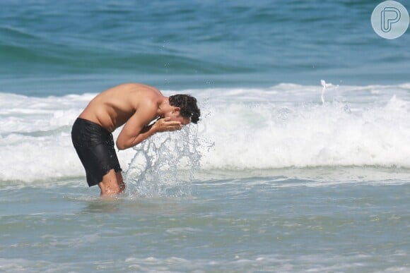 Cauã Reymond lava o rosto antes de mergulhar no mar da praia da Joatinga, Zona Sul do Rio