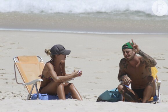 Felipe Titto acenou para o paparazzo que o flagrou na praia com a mulher