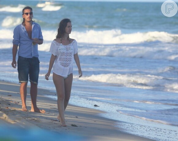 Nathália Dill e o namorado caminham juntos na praia