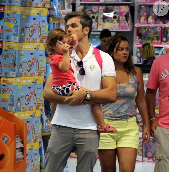 Otaviano Costa visita loja de brinquedos com a pequena Olívia no colo