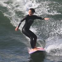 Daniele Suzuki surfa acompanhada de instrutor em praia carioca