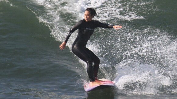 Daniele Suzuki surfa acompanhada de instrutor em praia carioca