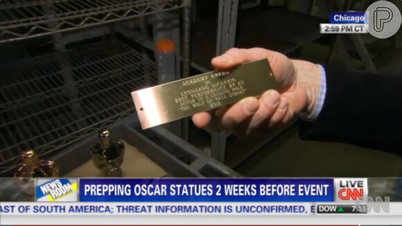 O repórter pega uma placa de um vencedor do prêmio da Academia para mostrar aos telespectadores como fica depois de pronta