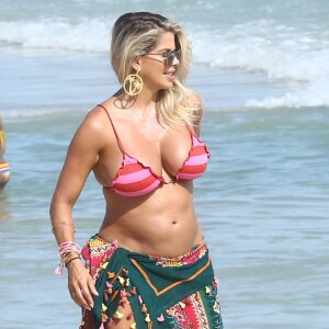 Karina Bacchi circulor pelas areias da praia exibindo sua barriguinha