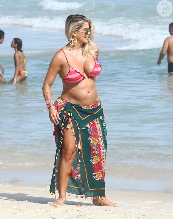 Karina Bacchi circulor pelas areias da praia exibindo sua barriguinha