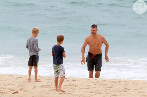Francisco e João assistem o pai, Rodrigo Hilbert, dar um mergulho no mar da areia da praia do Leblon, Zona Sul do Rio de Janeiro