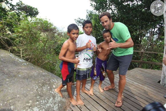 Jack Johnson posa com crianças durante visita à Prainha, na Zona Oeste do Rio de Janeiro