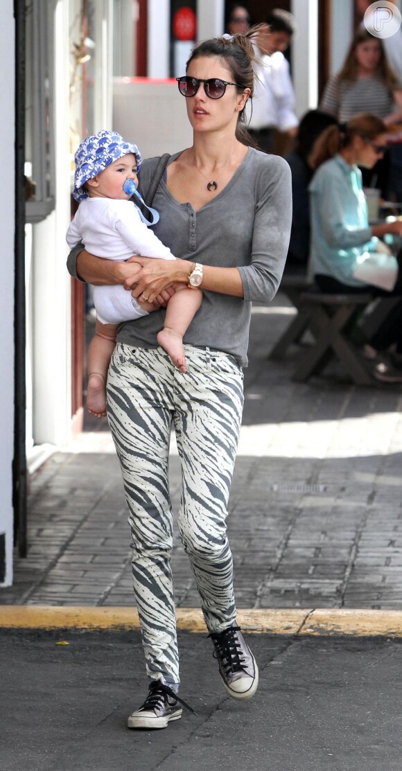 Alessandra Ambrósio carrega o filho, Noah, que usa um chapeuzinho de sol estampado
