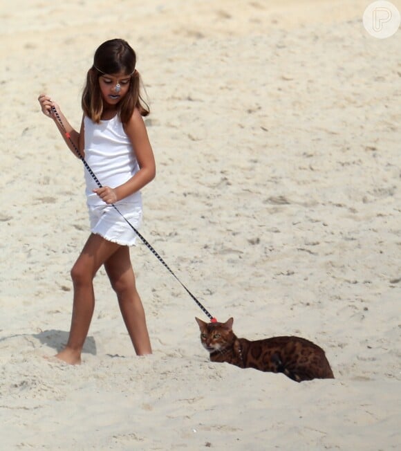 Sofia, filha de Cauã e Grazi, passeia com o gato usando uma coleira