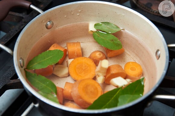 Em uma panela, coloque para cozinhar a cenoura, o gengibre picado, a cebola e o louro