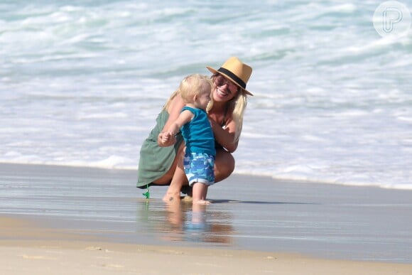 Karina Bacchi molha os pés do filho, Enrico, no mar da praia da Barra