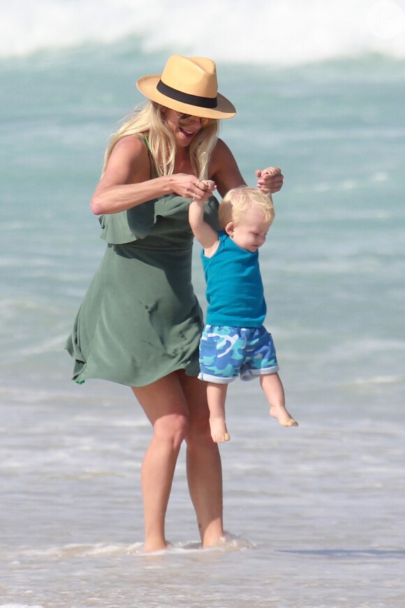 Karina Bacchi escolheu um vestido verde militar e chapéu para o dia na praia em família
