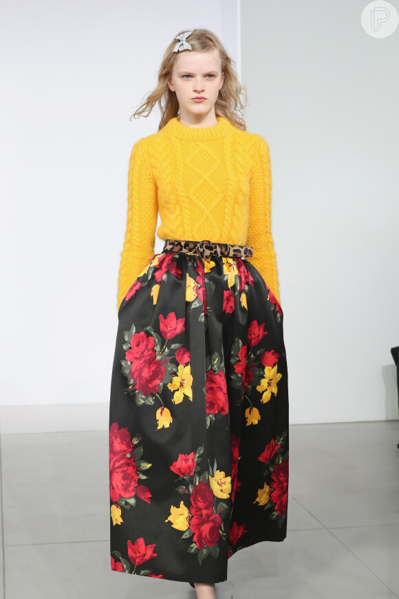 Aqui, a saia floral ganha modernidade quando usada com suéter em amarelo-ouro e cinto com animal print